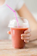 close up of woman holding cup with smoothie