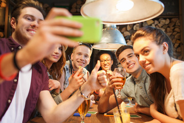 happy friends with smartphone taking selfie at bar