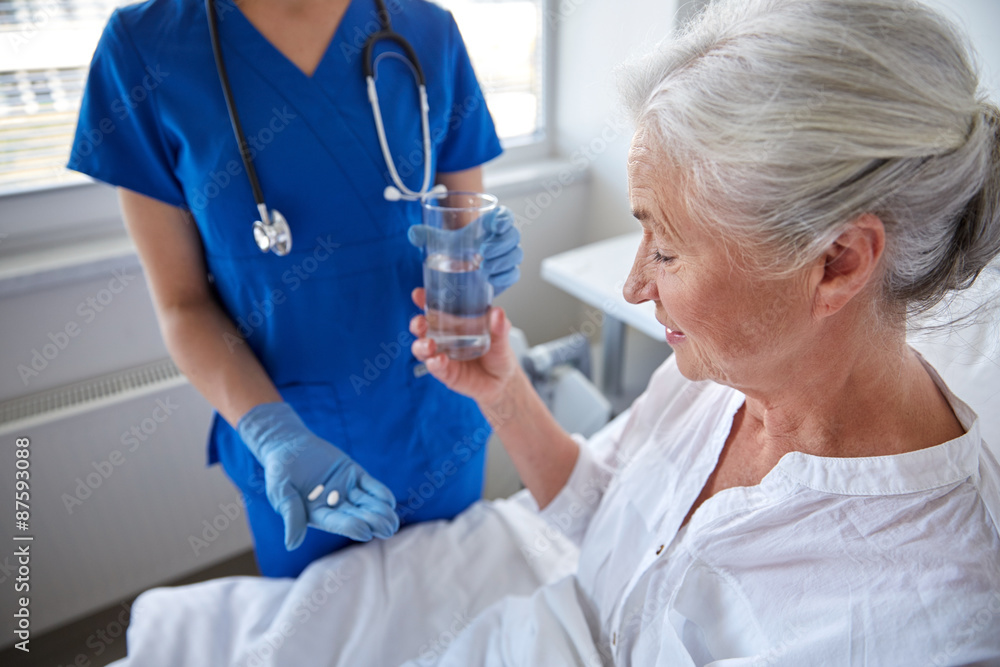 Poster nurse giving medicine to senior woman at hospital