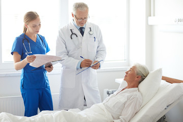 Obraz na płótnie Canvas doctor and nurse visiting senior woman at hospital