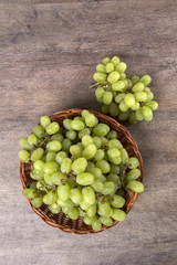 Green grapes in a basket over a wooden surface on a grape field