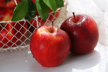 Ripe red apples in metal basket on windowsill