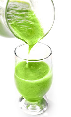 Pouring green healthy juice in glass isolated on white