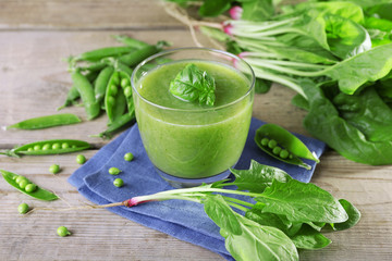 Glass of green healthy juice with spinach and peas on table close up
