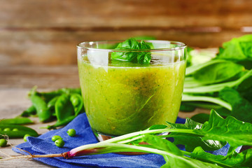 Glass of green healthy juice with spinach and peas on table close up