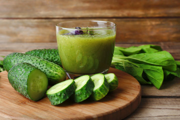 Glass of green healthy juice with spinach and cucumbers on table close up