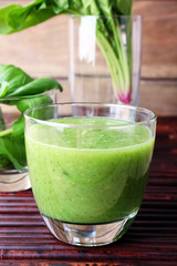 Glass of green healthy juice with spinach and basil on table close up