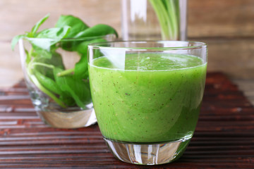 Glass of green healthy juice with spinach and basil on table close up