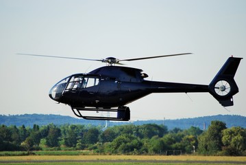Schwarzer Hubschrauber im Flug dicht über dem Boden © ArndtLow