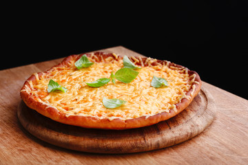 Tasty cheese pizza with basil on black background