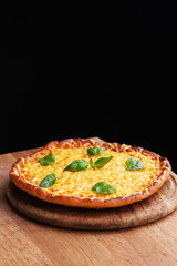 Tasty cheese pizza with basil on black background