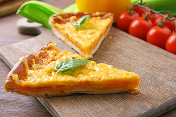 Slices of tasty cheese pizza with basil and vegetables on table close up