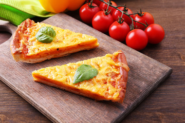 Slices of tasty cheese pizza with basil and vegetables on table close up