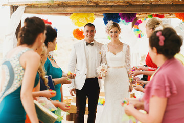 beautiful  gorgeous blonde bride  and stylish groom under confetti, hawai  colorful sand ceremony  on cyprus