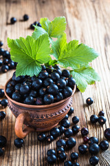 Blackcurrant in ceramic mug on rustic wooden board