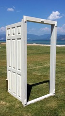 Fototapeta premium White open door on the grass overlooking the sea