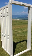 Fototapeta premium White open door on the grass overlooking the sea