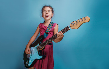 Girl European appearance ten years playing guitar sings on a blu