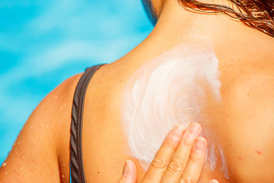 A mother applying a protect sun cream on the back of her young girl