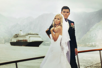 Stylish young bride and groom pose on board the yacht Montenegro