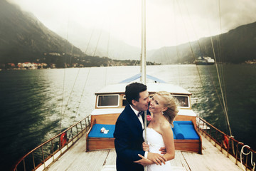 Stylish young bride and groom huging and smiling on board the yacht Montenegro on board the yacht Montenegro