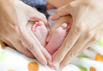 Obraz na płótnie Canvas newborn baby feet on mom and dad hands, shape like a lovely hear