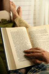 Naklejka premium Young man reading book on sofa close up