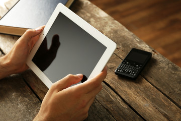 Hands holding digital tablet on wooden table background