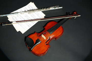 Fototapeta na wymiar Violin and flute with music notes on dark background