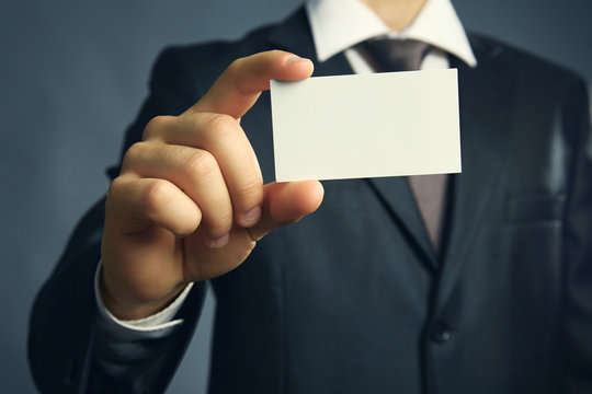 Handsome businessman holding business card close up