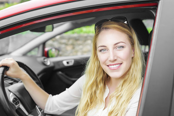Smiling young pretty blonde woman in the car, close-up.