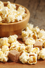 Caramel popcorn poured from a wooden bowl, selective focus