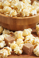Caramel popcorn poured from a wooden bowl, selective focus