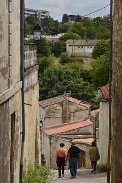 Fototapeta Promeneurs empruntant une ruelle à forte pente vers une vallée à Saintes 