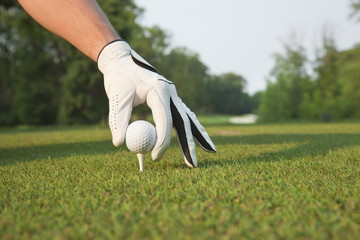 Selective foccus of golfer's hand placing ball on tee