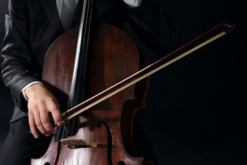 Man playing on cello on dark background