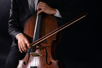 Man playing on cello on dark background