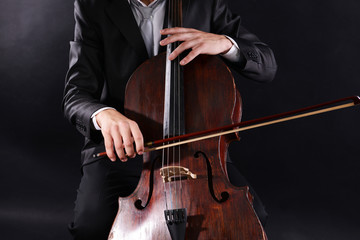 Man playing on cello on dark background © Africa Studio