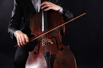 Man playing on cello on dark background