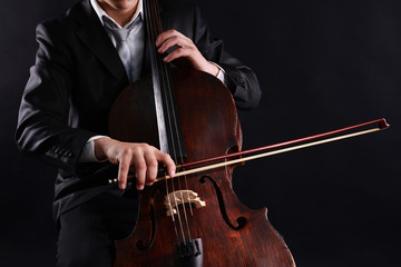 Man playing on cello on dark background