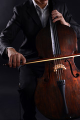 Man playing on cello on dark background