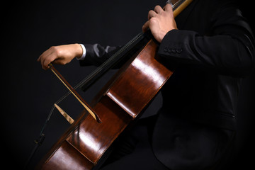 Man playing on cello on dark background