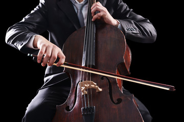 Man playing on cello on dark background © Africa Studio