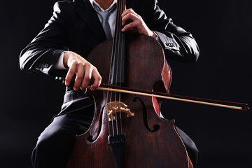 Man playing on cello on dark background © Africa Studio