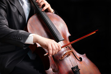 Man playing on cello on dark background