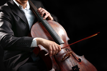 Man playing on cello on dark background © Africa Studio
