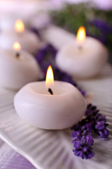 Fototapeta na wymiar Candles with lavender flowers on table close up
