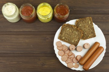 Poultry sausages on a wooden table, preparing home-made snacks. Ingredients for seasoning sausages.
