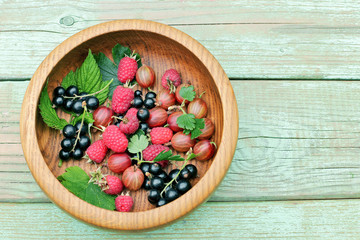 Wooden plate with summer assorted berries. top view