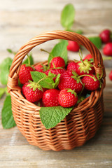 Fototapeta na wymiar Ripe strawberries in wicker basket on wooden table, closeup